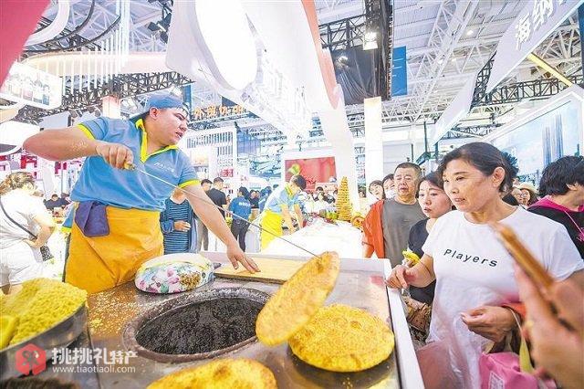 图为市民品尝新鲜出炉的烤馕，感受热气腾腾的制作过程