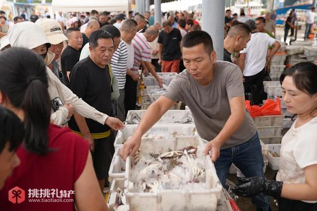 图为经营水产的殷加美正在招呼顾客