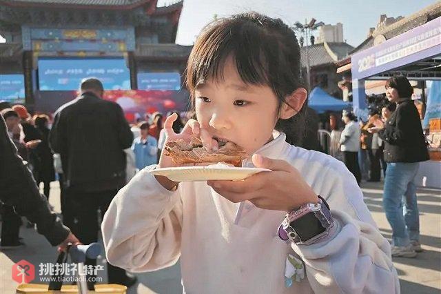 图为小顾客在品尝美味的烤全羊